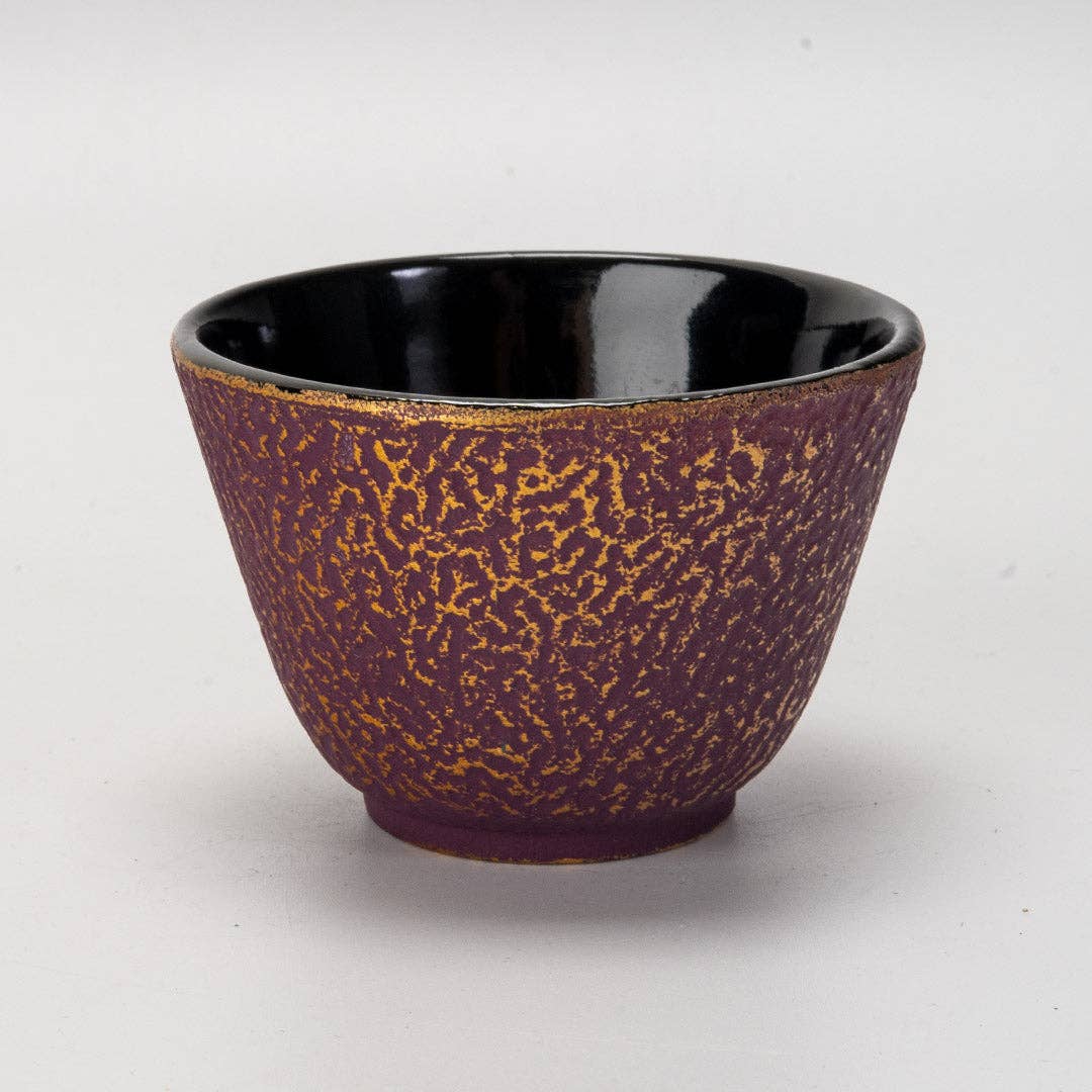 Close-up of purple honeycomb textured cast iron drinkware cup with deep glossy black interior on white background
