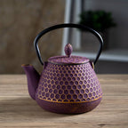 Purple cast iron teapot with honeycomb texture and black handle sitting on a wooden surface in soft light
