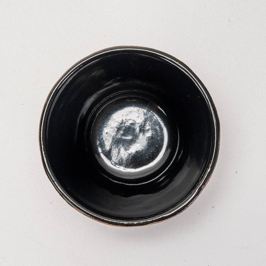 Top-down view of glossy deep purple cast iron drinkware with smooth glaze and subtle honeycomb texture inside bowl.