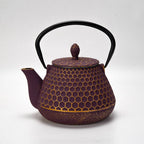 Deep purple cast iron teapot with honeycomb texture, curved spout, and black handle on a white background.
