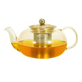 Clear glass teapot with stainless steel infuser basket filled with amber-colored brewed tea on white background