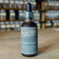 Dark amber tincture bottle with dropper labeled Happy Calm stress relief formula on wooden table