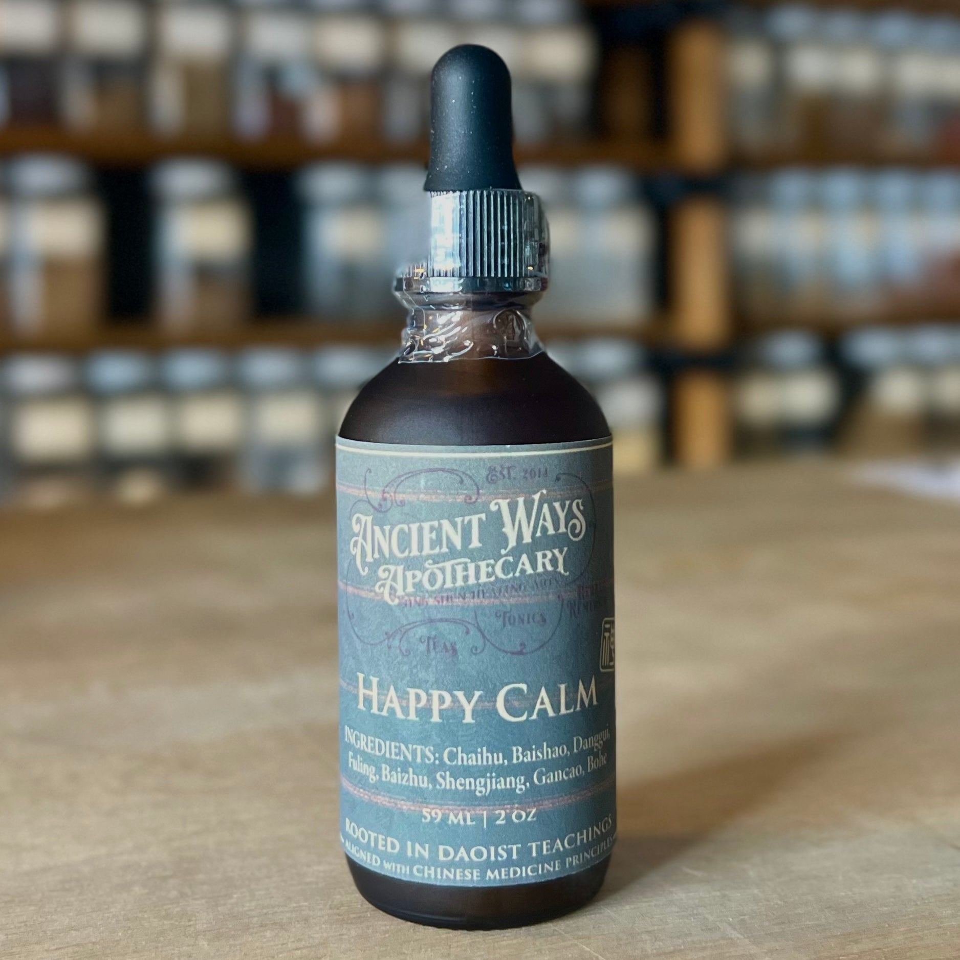 Dark amber tincture bottle with dropper labeled Happy Calm stress relief formula on wooden table