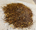 Close-up of Abundant Splendor honeybush tea blend with apricot and floral notes, naturally caffeine-free on parchment paper.