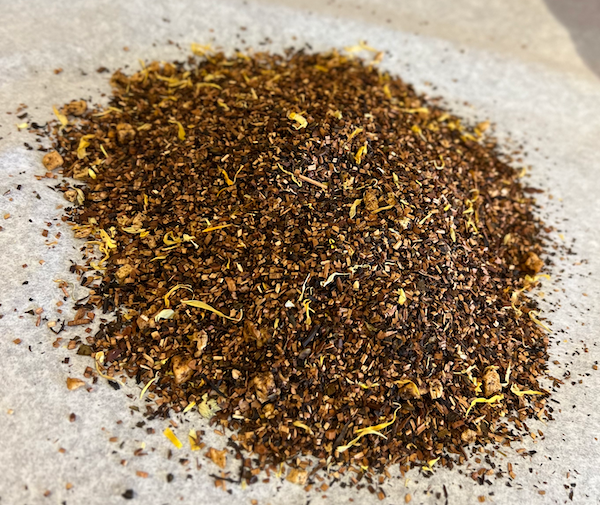Close-up of Abundant Splendor honeybush tea blend with apricot and floral notes, naturally caffeine-free on parchment paper.