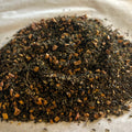 Loose Apple Crisp green tea blend with dried apple pieces and warming spices on parchment paper close-up