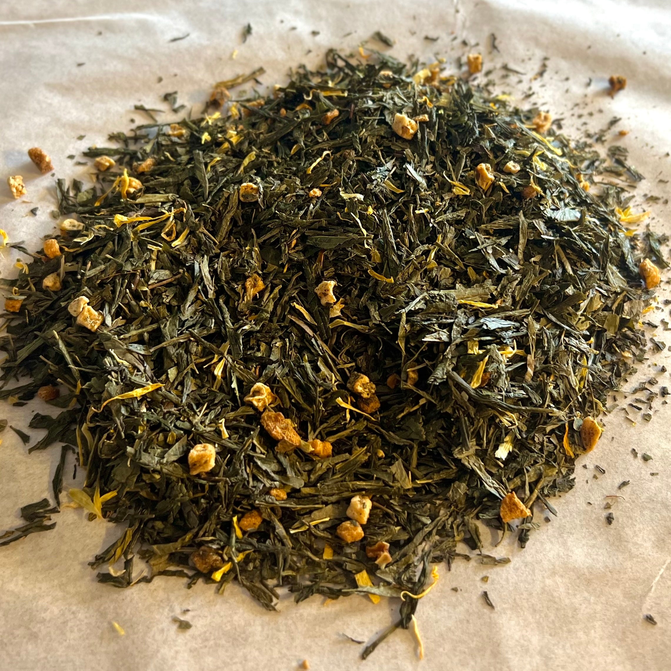 Close-up of Apricot Breeze loose green tea blend with apple pieces and dried apricot bits on parchment paper.