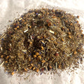 Close-up of loose Banana Berry Rooibos tea blend with green rooibos, strawberry pieces, and banana bits on parchment paper