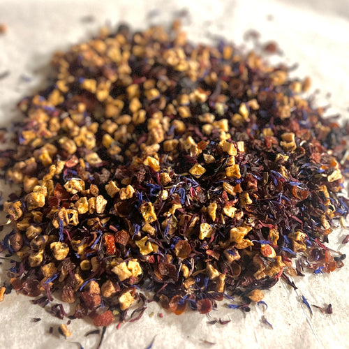 Close-up of Berries & Créme loose tea blend with dried rose hips, hibiscus petals, apple pieces, and berry fragments.