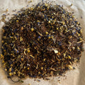 Loose blend of Big Citrus Skies tea with rooibos, black tea, orange zest, lemongrass, and chamomile flowers on paper background