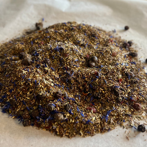 Loose Blue Green Dragon rooibos tea blend with green rooibos, blueberries, and natural caffeine-free ingredients on paper.