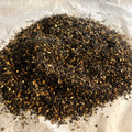 Close-up of Chai No. 71 loose tea blend with black tea, cinnamon, ginger, and cocoa nibs on parchment paper.