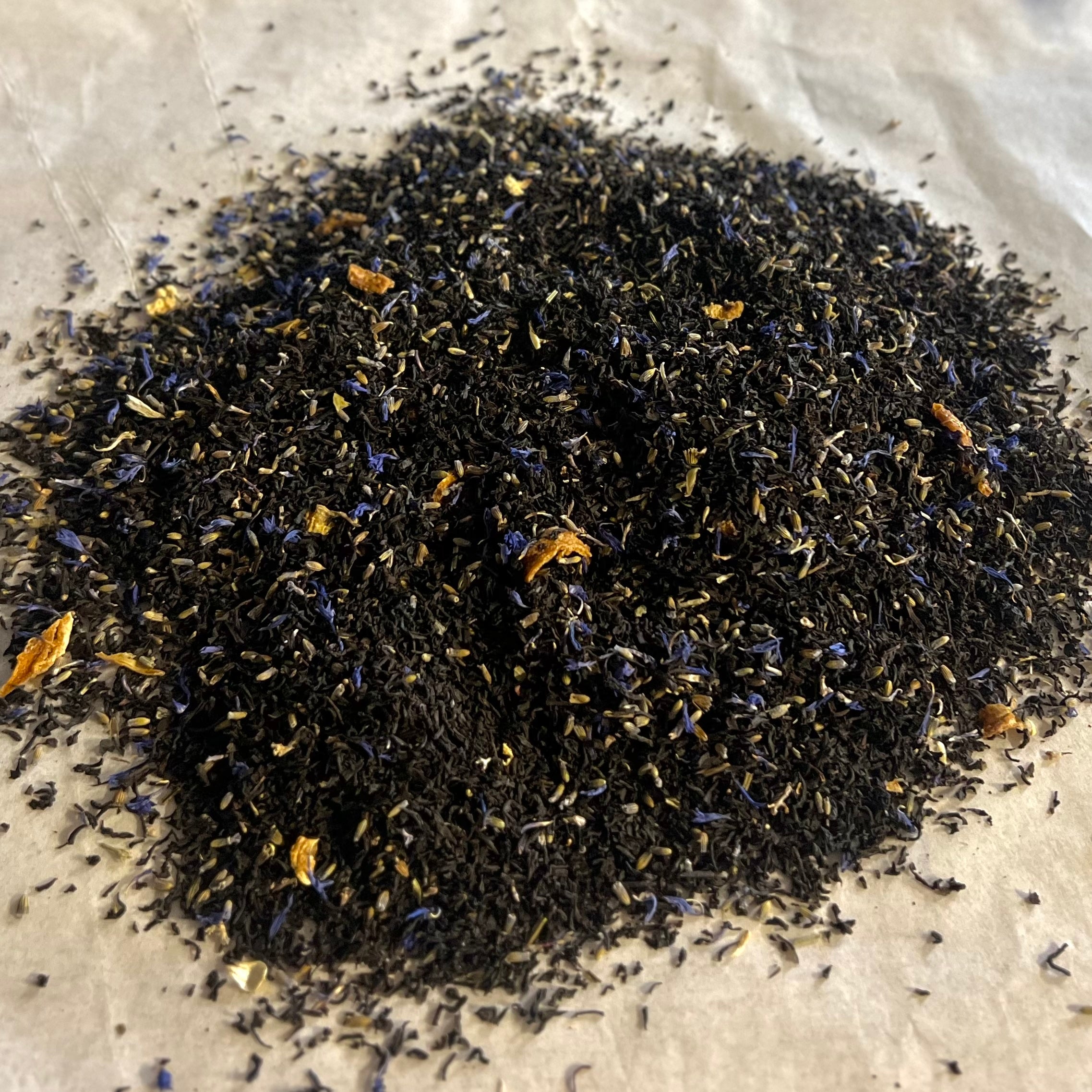 Close-up of Courtyards of Lavender Earl Grey loose black tea blend with lavender buds and citrus peel on parchment paper.