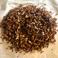 Close-up of Elderberry Island Twist loose tea blend with dried elderberry, apple, hibiscus, rosehip, mango, pineapple, and orange pieces on parchment.