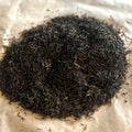 Close-up of loose English Breakfast black tea blend with dark Assam and Ceylon leaves on parchment paper background