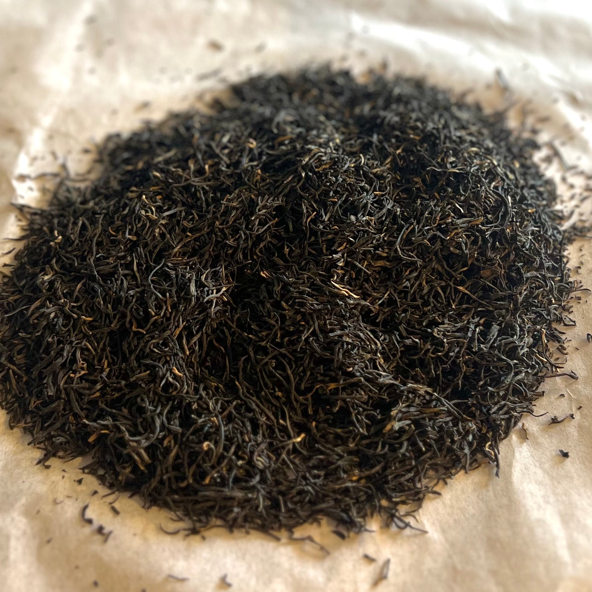 Close-up of loose English Breakfast black tea blend with dark Assam and Ceylon leaves on parchment paper background