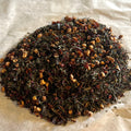 Loose Flathead Cherry Goodness tea blend with dark green Sencha leaves and dried cherry pieces on parchment paper