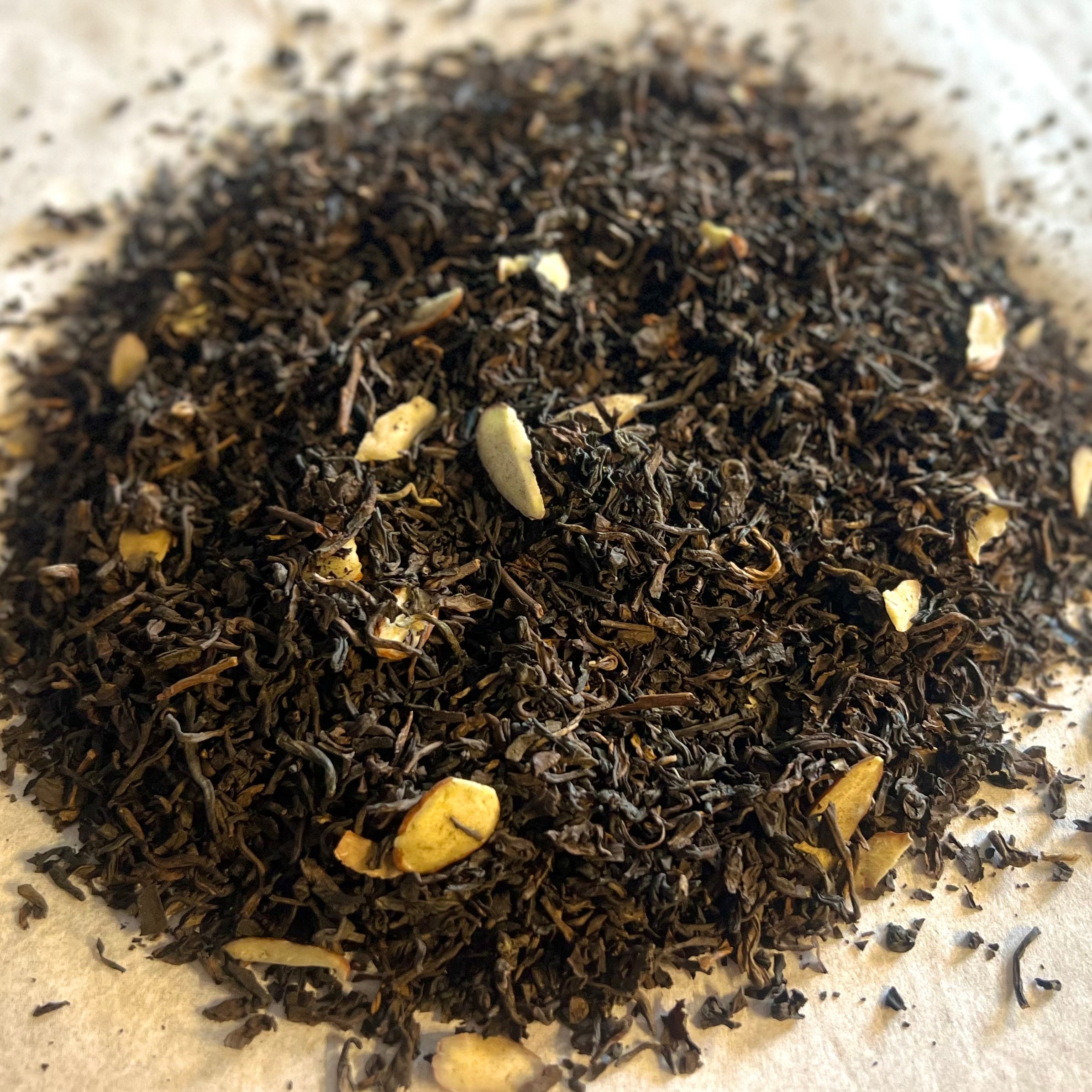 Close-up of Highland Caramel tea blend with dark Scottish pu-er leaves and caramel pieces on natural paper background
