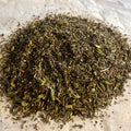Close-up of Chai No. 74 loose tea blend with roasted green tea, spearmint, chai spices, and hojicha pieces on parchment paper