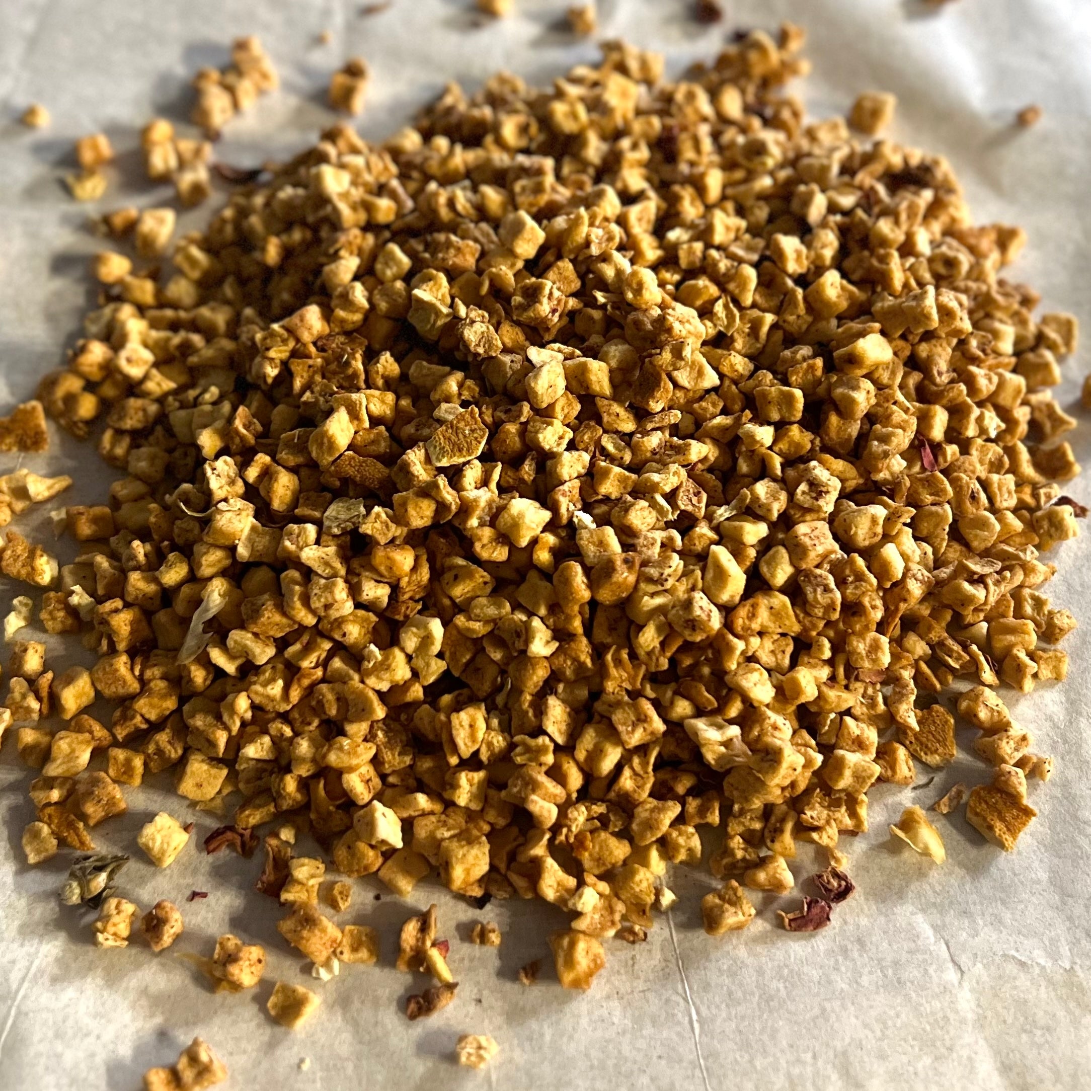 Close-up of dried peach pieces for Just Peachy fruit and flower tea blend on light surface, naturally caffeine-free.