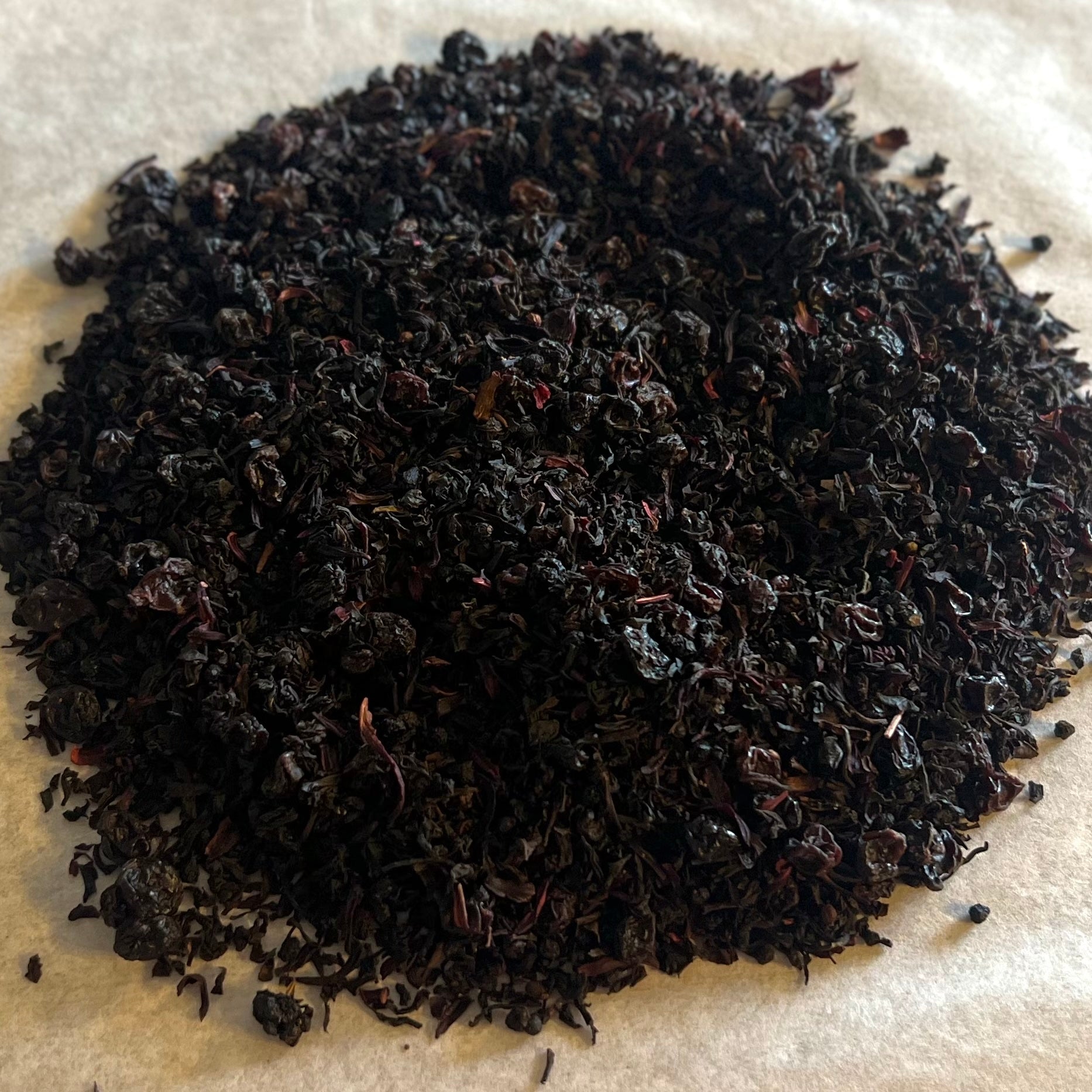 Close-up of Merlot Mornings loose tea blend with dark, finely textured leaves evoking rich berry and wine notes.