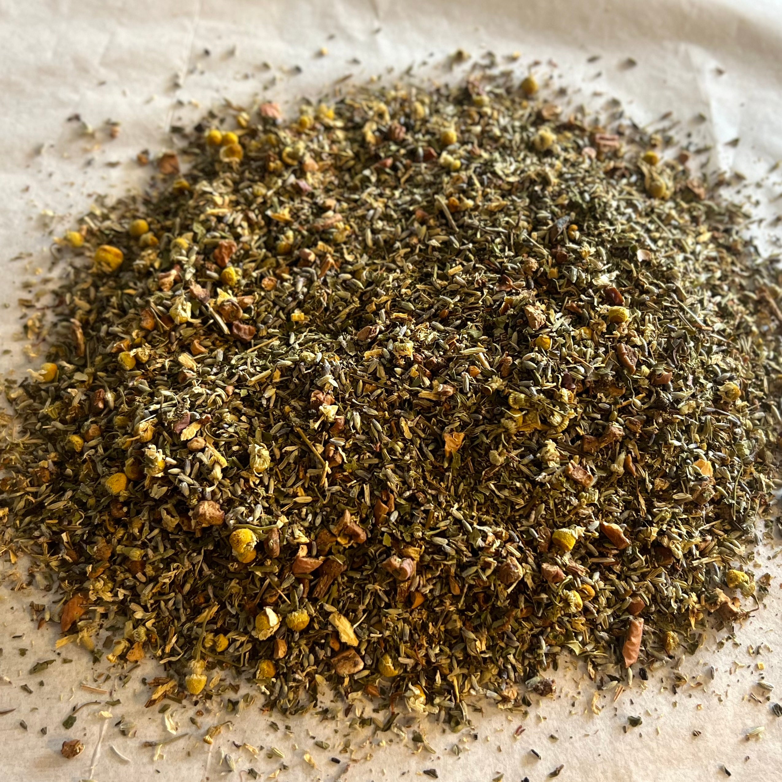 Close-up of loose Montana Dream sleep tea blend with chamomile, lavender, lemon balm, and valerian on parchment paper.