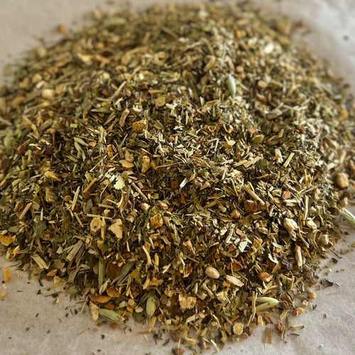 Close-up of 3 Mile Tea loose herbal blend with roasted yerba mate and mixed herbs on a light surface