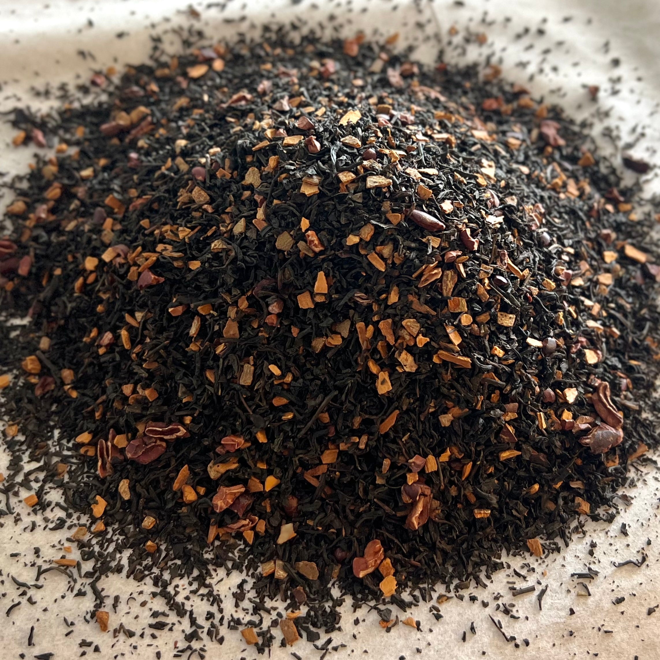 Loose Black Tea blend with dark leaves and small cinnamon and chocolate pieces on neutral background