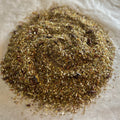 Close-up of loose Coconut Dream rooibos tea blend with toasted coconut flakes and cacao nibs on parchment paper background