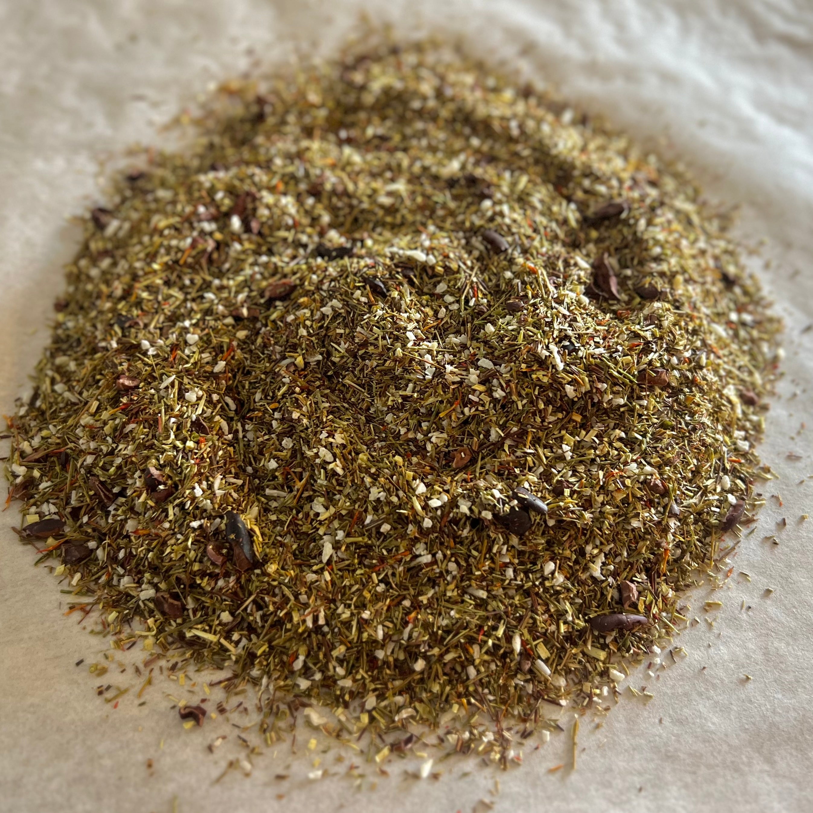 Close-up of loose Coconut Dream rooibos tea blend with toasted coconut flakes and cacao nibs on parchment paper background