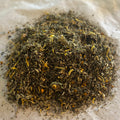 Close-up of Flower Covering loose herbal tea blend with mullein, marshmallow, elecampane root, and yellow flower petals on parchment paper
