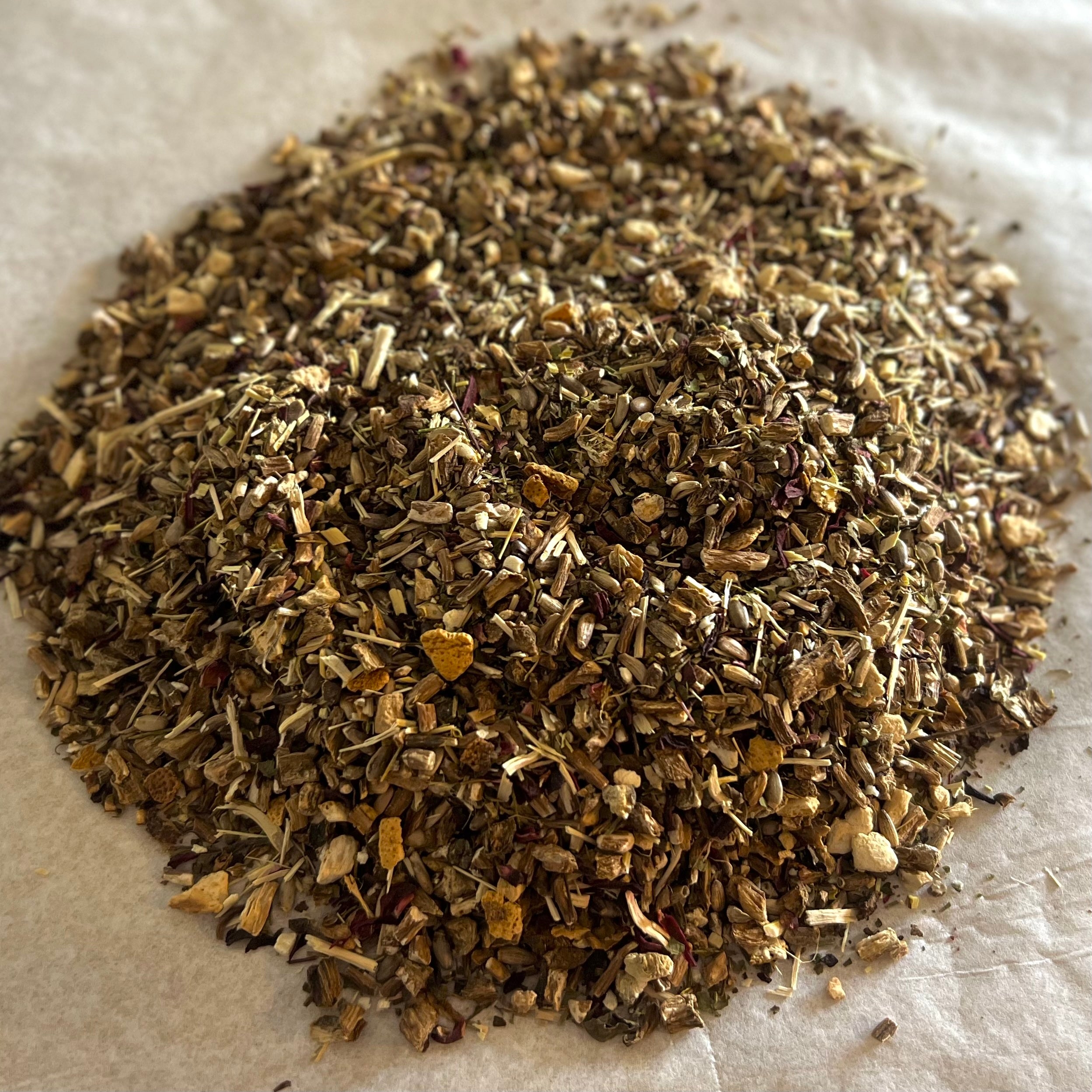 Close-up of Happy Liver herbal tea blend with dandelion, burdock, and milk thistle pieces on a light surface