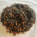 Loose Jasmine Oolong tea leaves mingled with delicate dried jasmine petals on a white surface, ready for brewing.