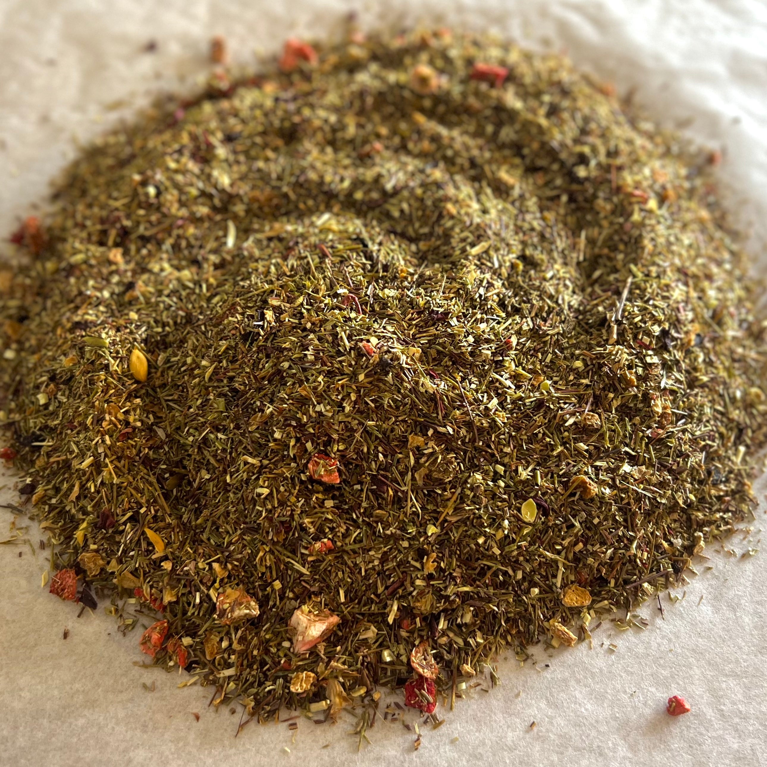 Close-up of Lemonberry Tart rooibos tea blend with dried strawberry pieces and lemon peel on parchment paper.