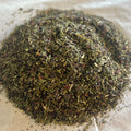 Close-up of loose Mint Blossoms herbal tea blend with dried peppermint and hibiscus petals on a light surface