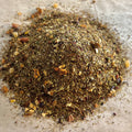 Close-up of Ruby-Red Dragon rooibos tea blend with dragonfruit, mango, apple pieces, and citrus peel on parchment paper