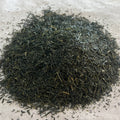 Loose Sencha Arihara Japanese green tea leaves, finely cut with a deep green hue on a light surface.