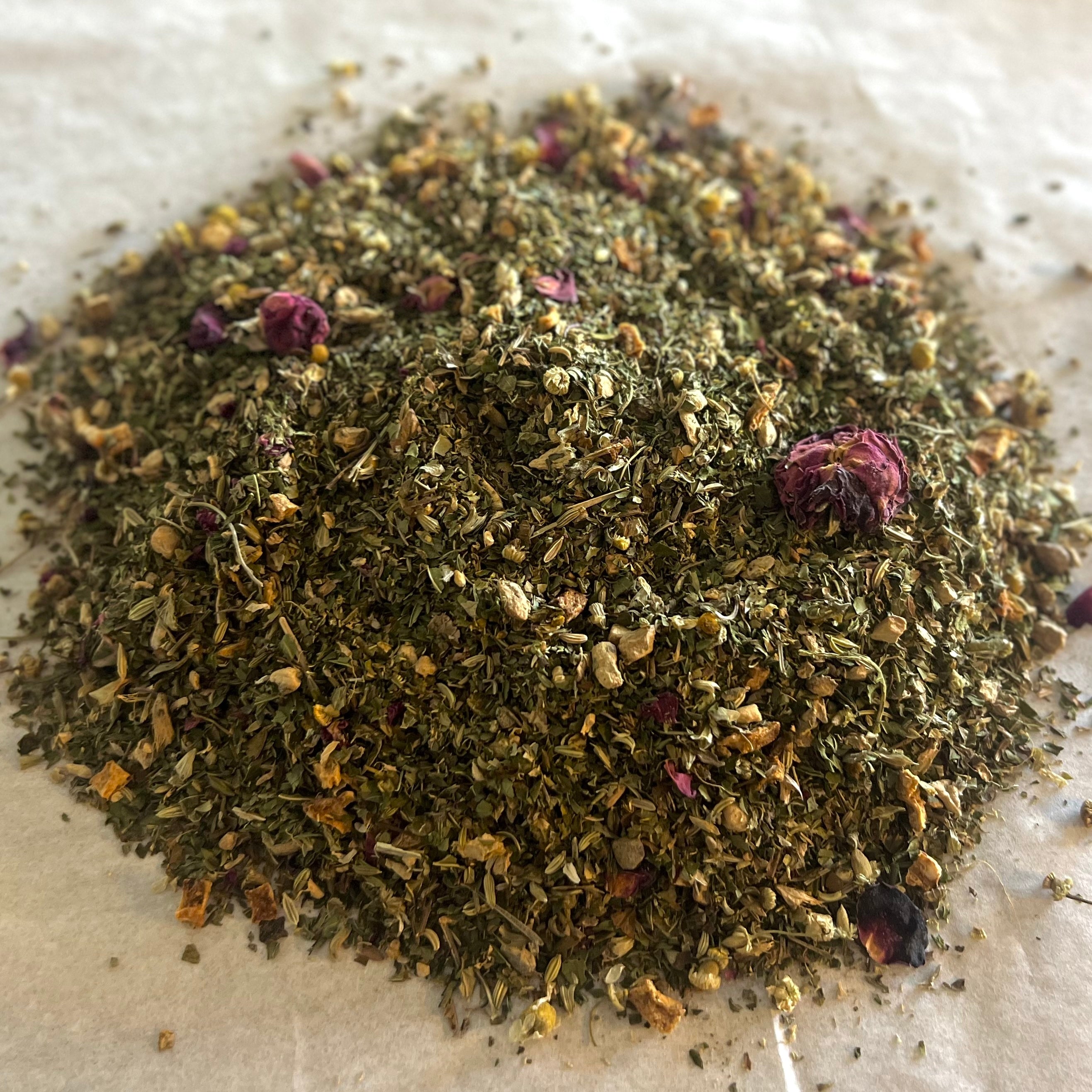 Close-up of loose Support | Digestion herbal tea blend with dried chamomile, peppermint, rosebuds, and natural herbs on parchment paper