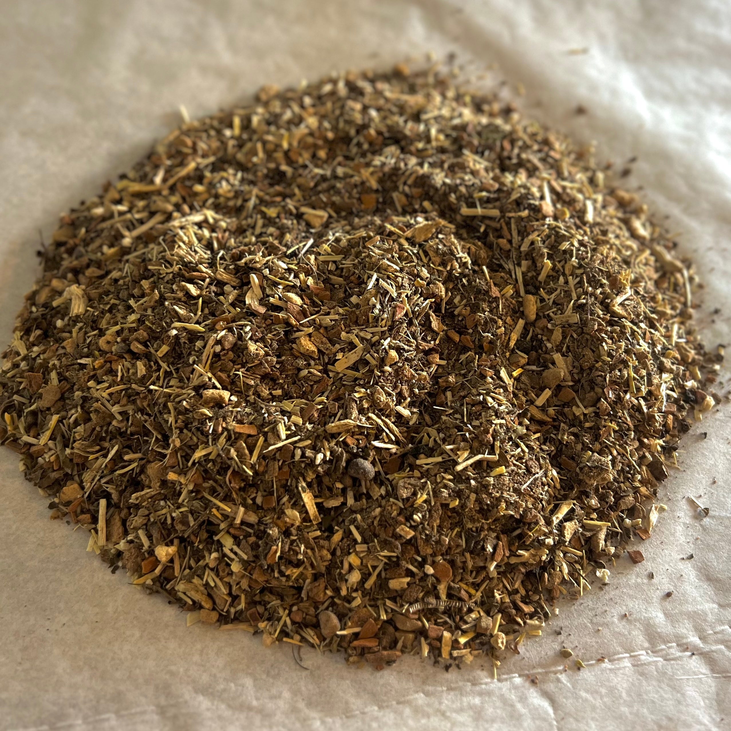 Close-up of Support | Him spiced herbal tea blend with eleuthero, astragalus, and fo-ti on parchment paper.