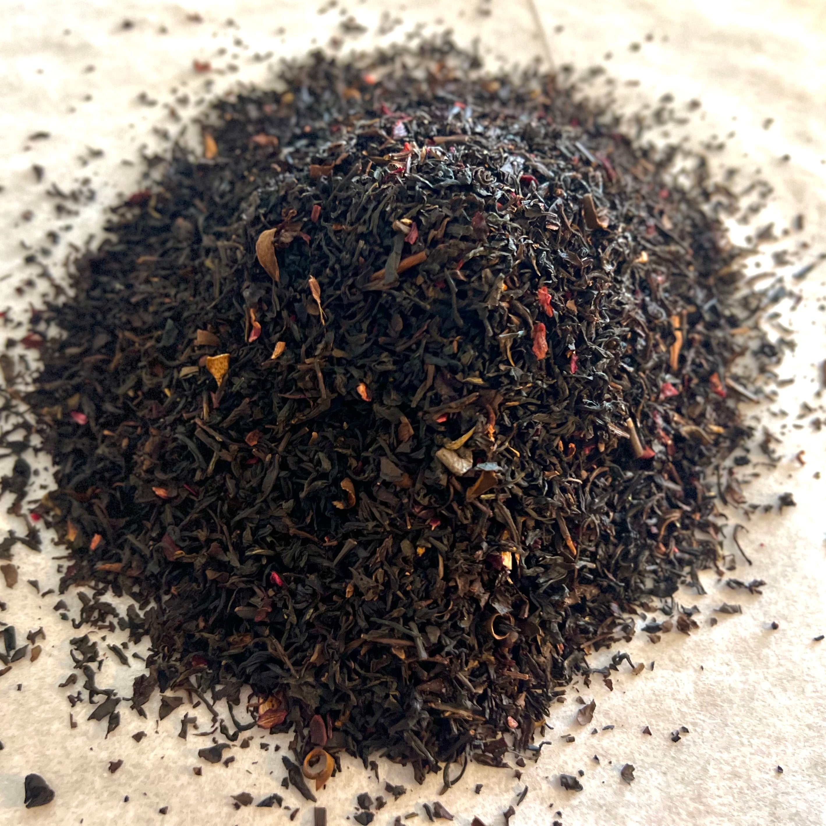 Close-up of Whiskey & Wit black tea blend with dark leaves and hints of spices on a light surface ready for brewing
