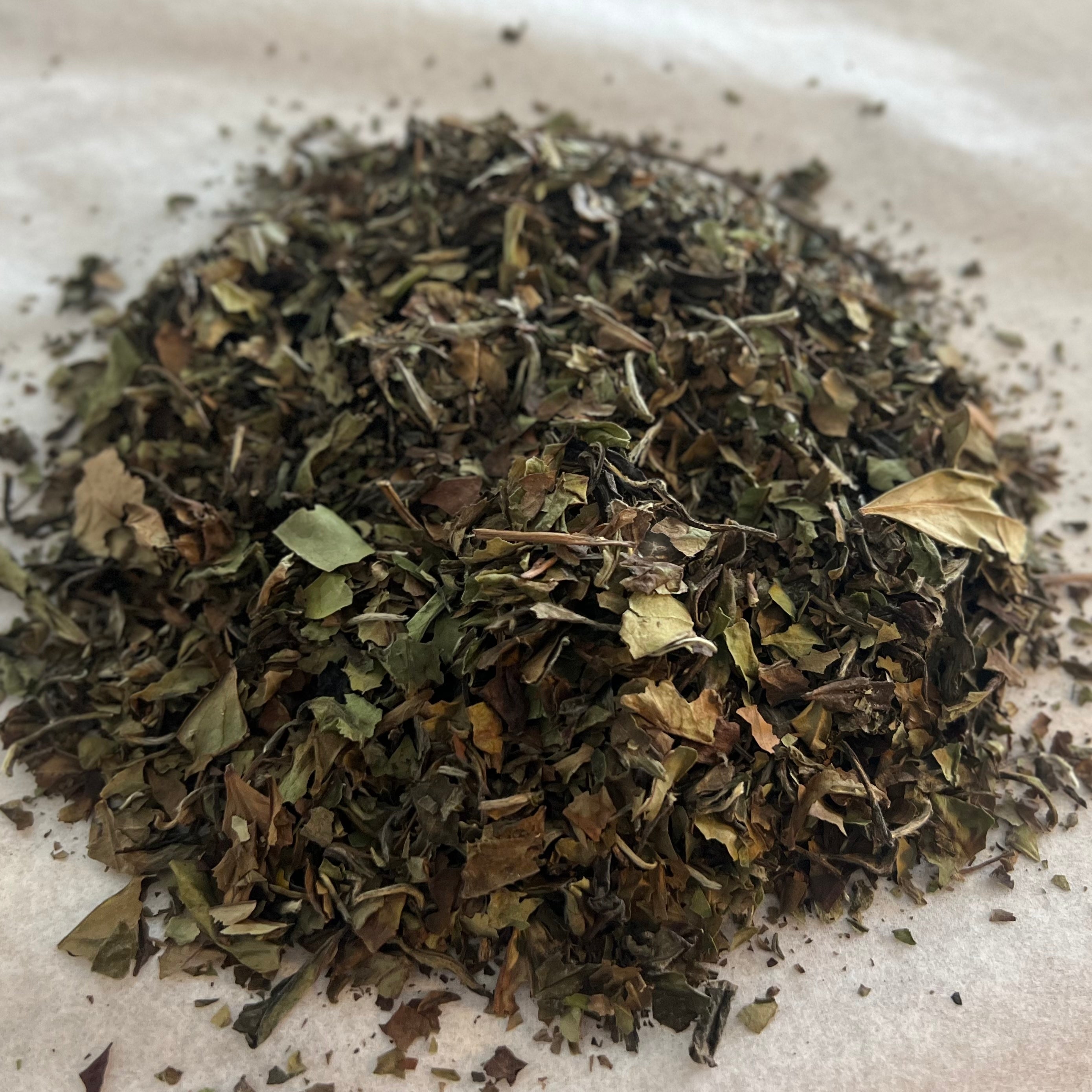 Loose Chinese white tea leaves with peony petals, light and delicate with subtle natural hues on a neutral surface