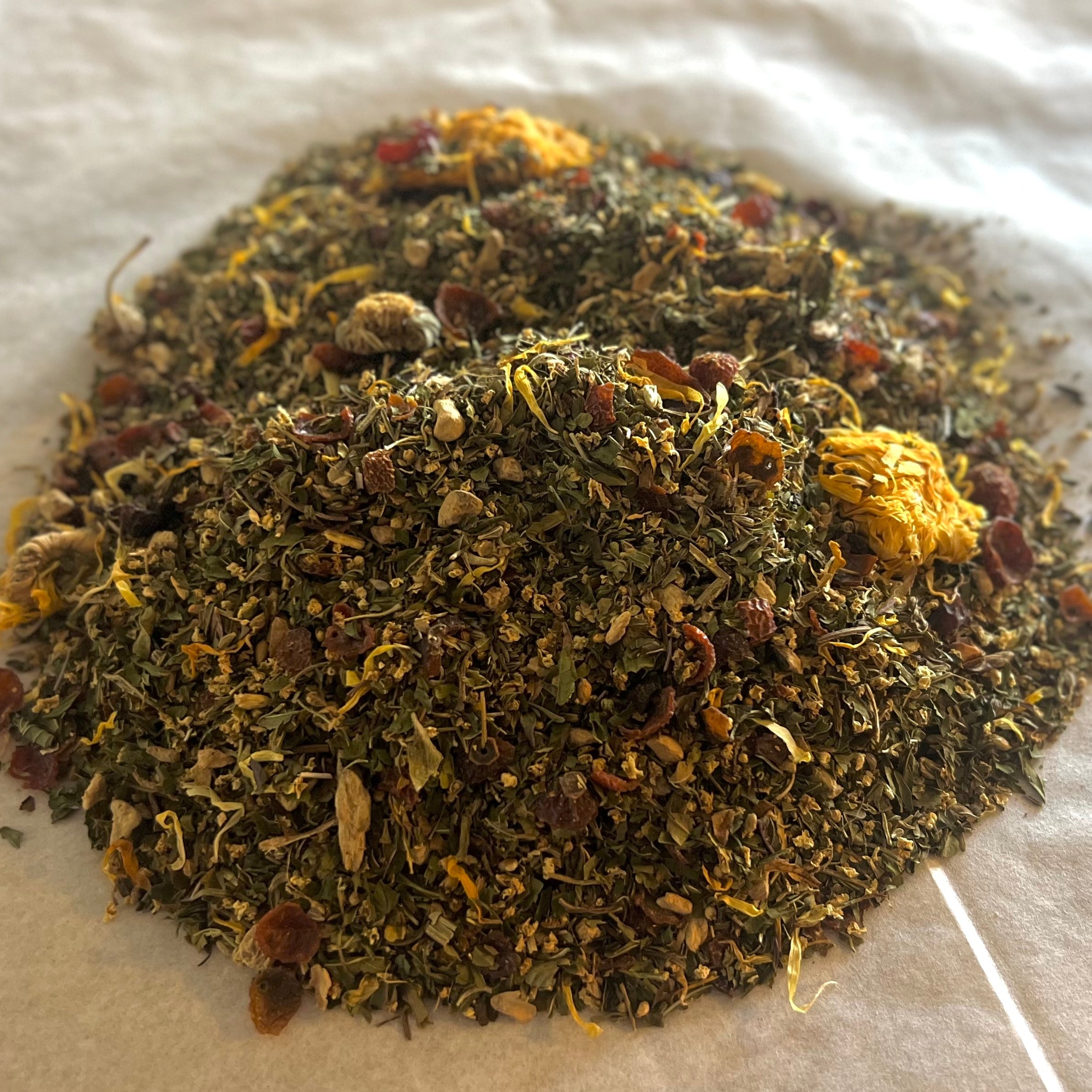 Close-up of Hammer Time herbal wellness tea blend with dried botanicals and herbs on a light fabric surface.