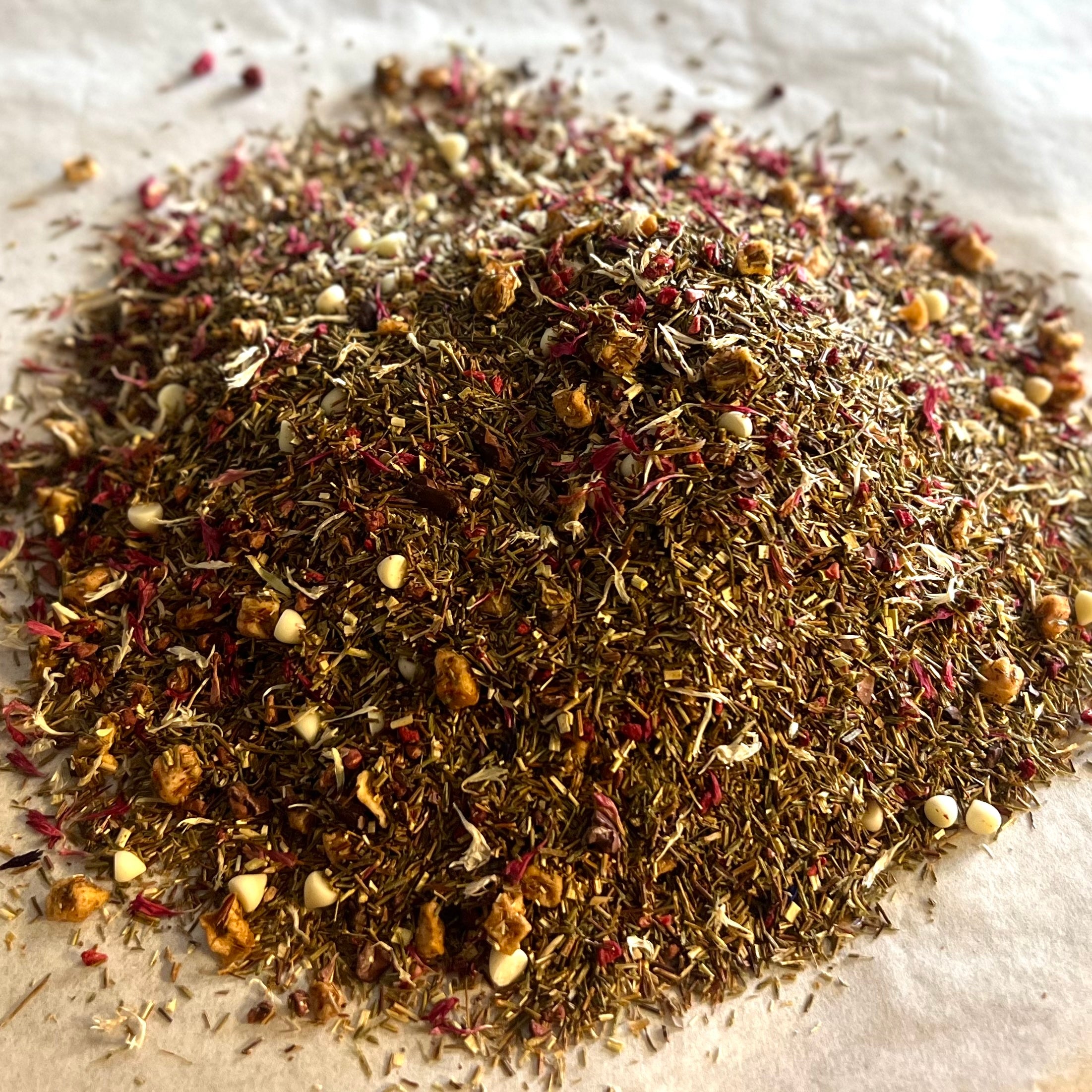 Close-up of loose Raspberry Truffle tea blend with green rooibos, apple pieces, mini white chocolate, and raspberry hints