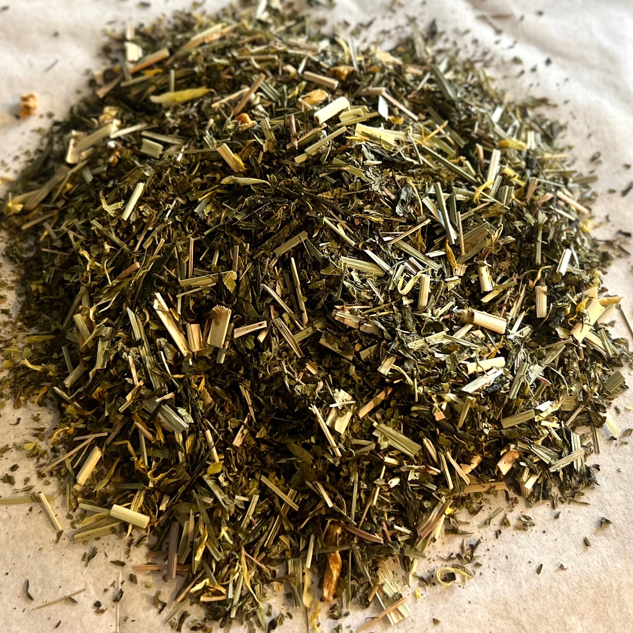 Close-up of Road to Happiness loose green tea blend with lemongrass and citrus peels on a light background