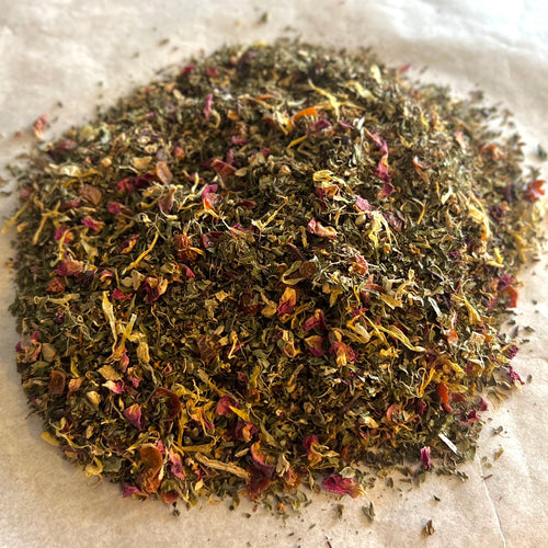 Close-up of Rose Mint Rooibos loose tea blend with rooibos leaves, rose petals, and dried mint leaves on light surface