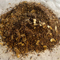 Close-up of loose Chai No. 78 tea blend with rooibos, chaga mushroom, and coconut flakes on parchment paper.