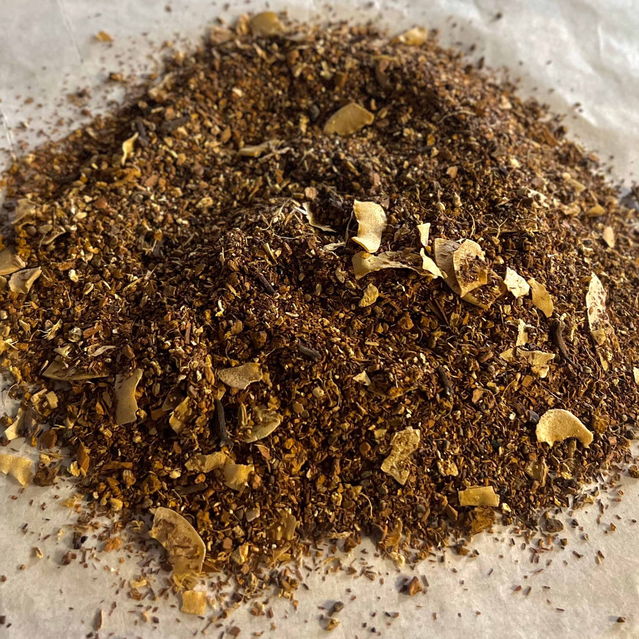 Close-up of loose Chai No. 78 tea blend with rooibos, chaga mushroom, and coconut flakes on parchment paper.