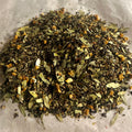 Close-up of Morning Momentum loose tea blend with green tea, mate, oolong, and herbal leaves on parchment paper surface