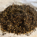 Close-up of Chai No. 32 loose tea blend with dark pu-erh leaves, cocoa nibs, and chai spices on a parchment surface