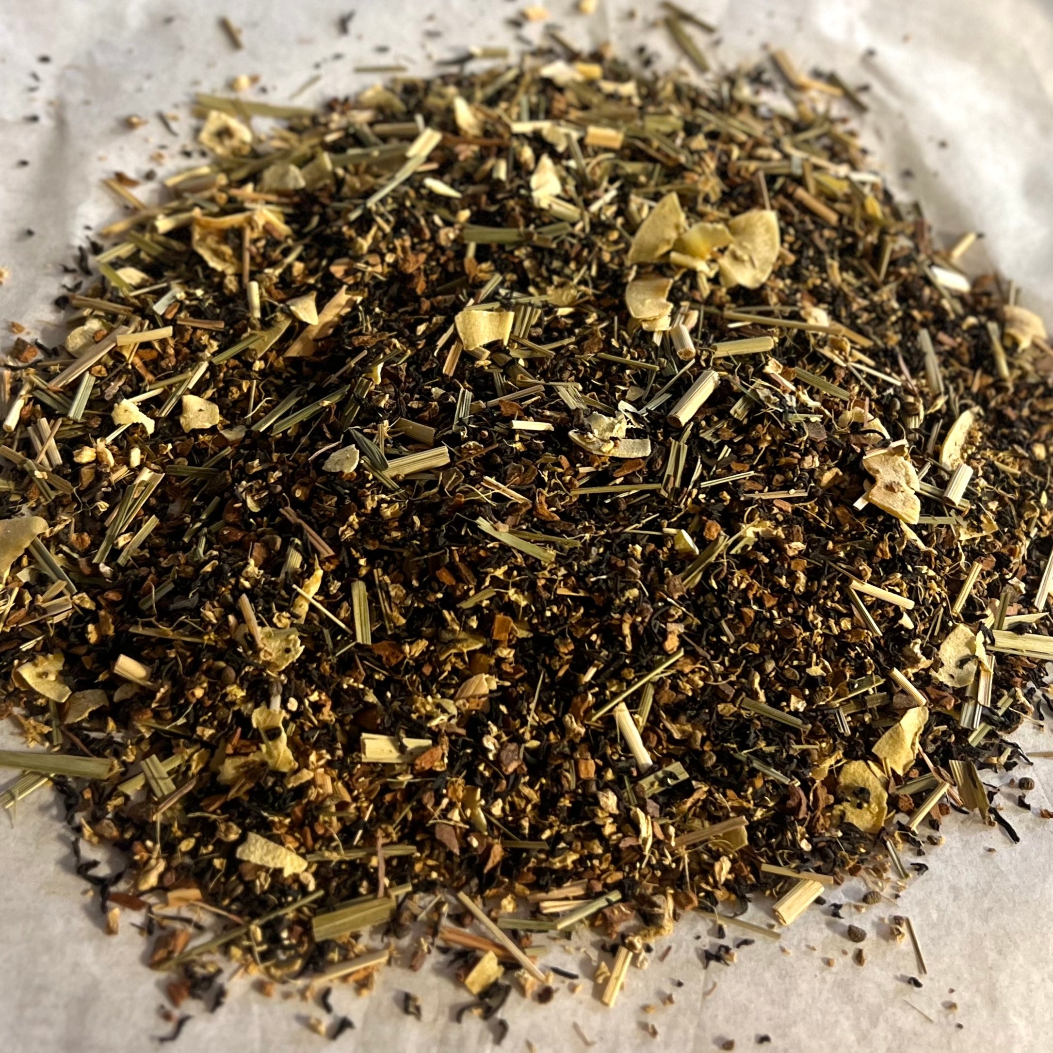 Close-up of No. 73 Chai loose tea blend featuring bold black tea leaves with creamy Thai-inspired spices on parchment paper.
